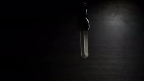 Spiral Fluorescent Lamp Flickering Illuminating and Swaying on an Electric Wire