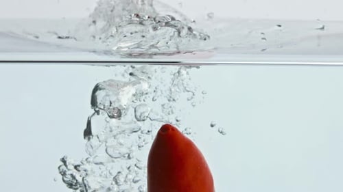 Red Pepper Splashing Liquid Surface Closeup. Fresh Spicy Vegetable Wash Bouncing In