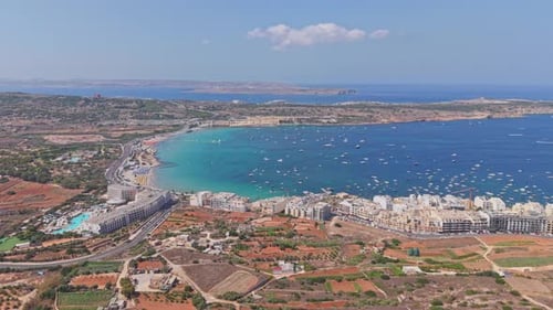 A panoramic aerial view of Mellieha Bay in Malta, showcasing its turquoise waters filled with boats