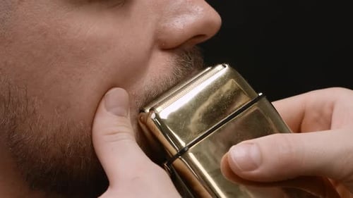Man Shaving Beard with Gold Electric Razor