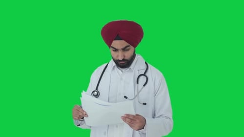 Serious Sikh Indian doctor checking medical reports Green screen