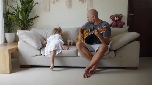 Man Plays Guitar for Child in Bright Living Room
