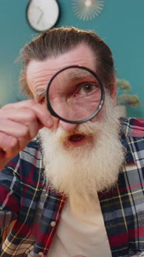 Senior Man with White Beard Examining with Magnifying Glass