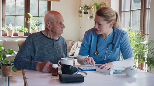 Senior Man and Caregiver Discuss Medication at Home