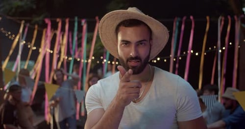 Man in Hat Signals Shhh at Night Party