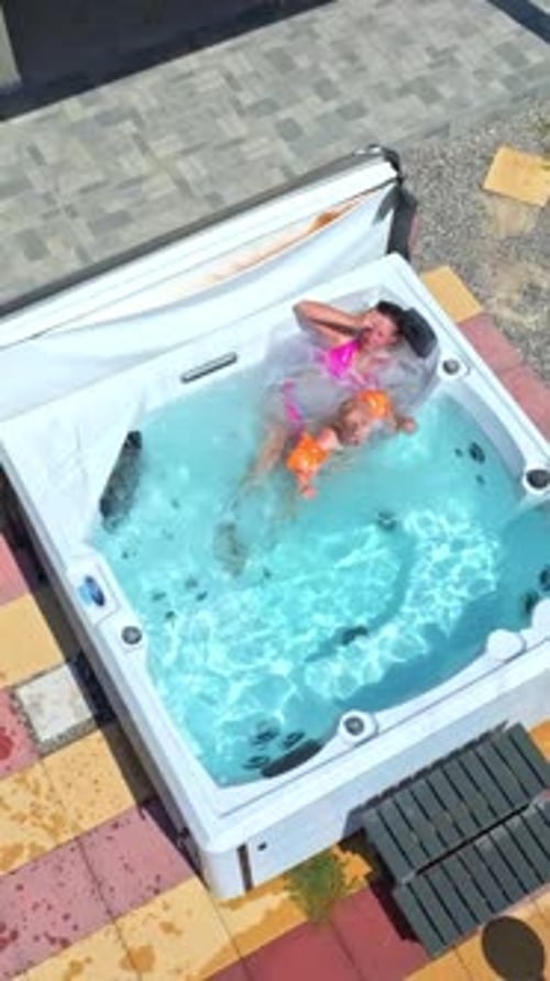 Drone vertical d'une mère et de son fils se relaxant dans un jacuzzi, journée ensoleillée