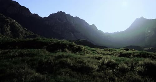 Serene Mountain Landscape at Dawn with Lush Grass and Rugged Peaks