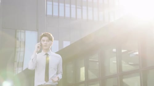 Portrait of young businessman in formal attire talks on mobile phone outside office center downtown
