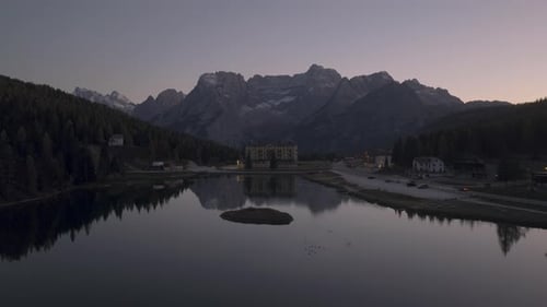 Vue aérienne cinématographique du Grand Hotel Misurina sur le lac Misurina au crépuscule avec des reflets calmes,