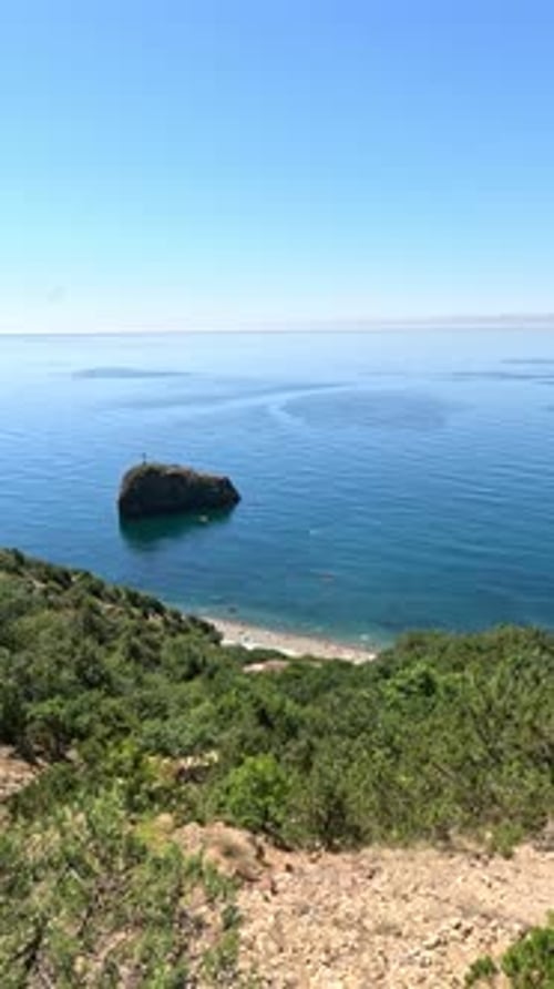 Vista aérea de un mar azul tranquilo y costas rocosas volcánicas, pequeñas olas en la superficie del agua en movimiento borroso