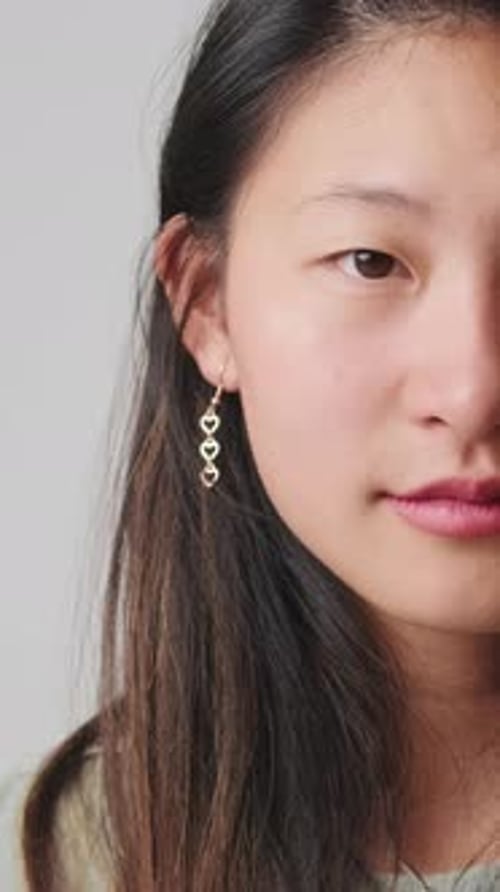 Close up, half face young woman looking at camera isolated over white background in studio