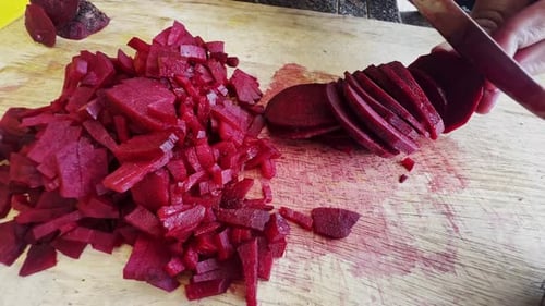 Close up of female hands in gloves cutting beet on kitchen board