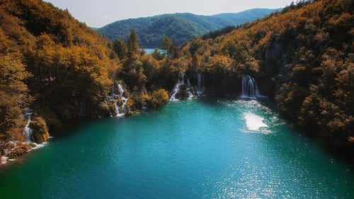 El río se extiende en arroyos de cascadas en el bosque otoñal. El agua desemboca en el lago. Bright Fall Co