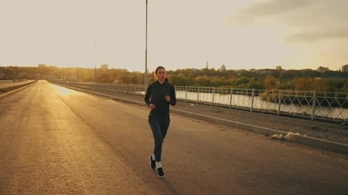 Athletic Woman is Running Alone on Road in Summer Morning or Evening Training in Sunny Weather