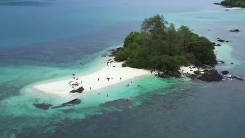 Aerial view drone shot of peoples on a tropical small island with trees, rocky and white sand beache