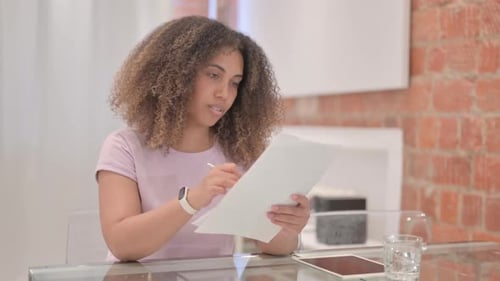Smiling Woman Reading Document at Desk
