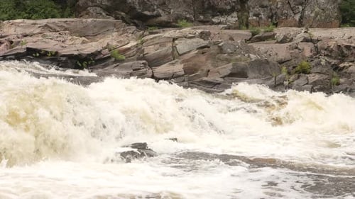 Powerful white water rapids cascading down a river in slow motion.