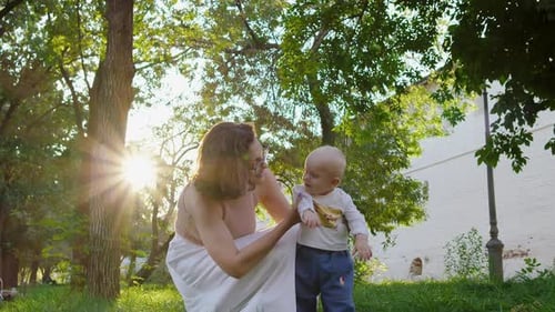 Mother Helping Baby Learn to Walk Outdoors