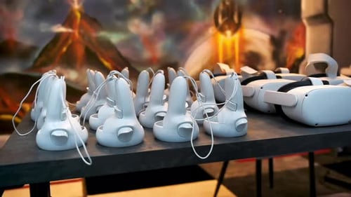 Vue rapprochée de plusieurs manettes et casques VR blancs sur une table. Ralenti