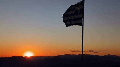 Greek Flag Waving at Sunrise Over Mountains