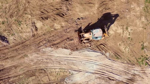Aerial View of an Excavator Leveling and Moving Earth on a Construction Site