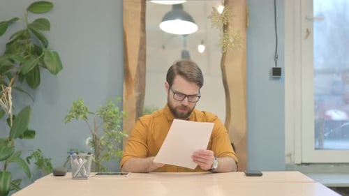 Young Businessman Reading Documents in Office