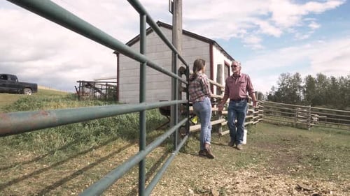 Rancher father and daughter talk in sunny pasture on picturesque rural ranch