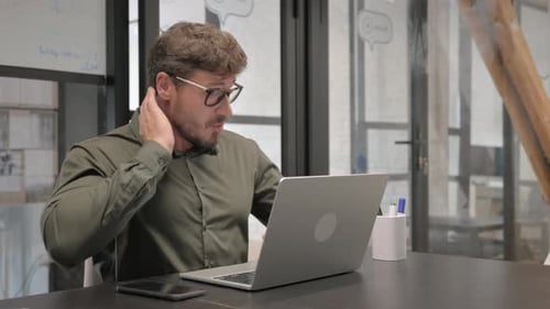 Man with Neck Pain Types on Laptop in Office