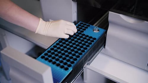 Gloved Hand Placing Tray into Diagnostic Machine