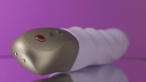 Close Up of New Modern Vibrating Sex Toy Lying on a Table on a Pink Wall Background Close Up of New Modern Vibrating Sex Toy Lying on a Table on a Pink Wall Background