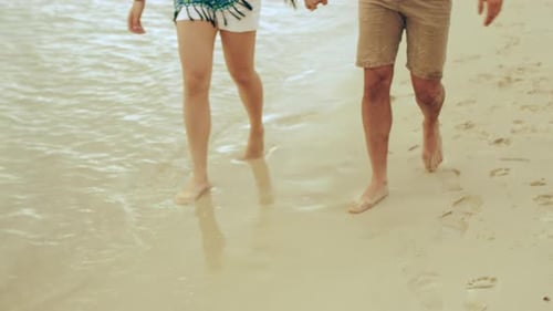 Couple Walking Along The Beach Holding Hands And Smiling Near Water In Australia. Medium Shot On ...