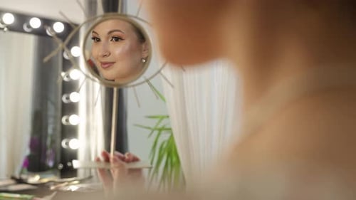 Beautiful Woman Appreciating Her Makeup Reflection in a Mirror