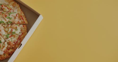 Top View of Traditional Pizza in Cardboard Box on Yellow Color Copy Space Background