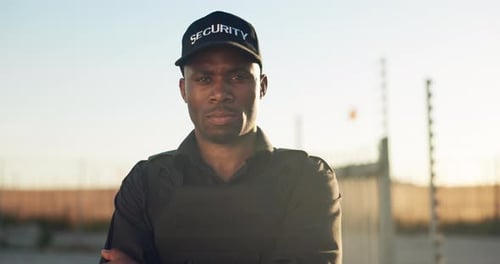 Security Guard in Uniform Standing in Front of Fence