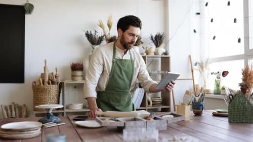 Bearded Adult Man in Apron and White Shirt Viewing an Online Course