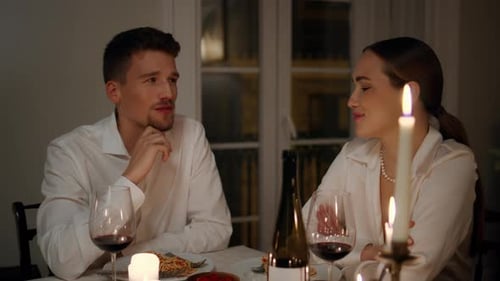 Couple talking over romantic candlelit dinner at home