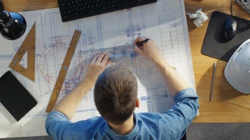 Top View of a Technical Engineer Working on His Blueprints, Drawing on Plans. Various Drawing Objec