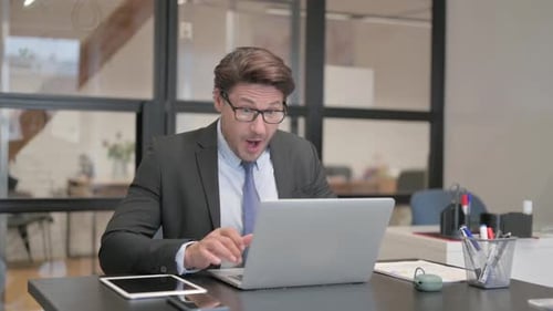 Excited Middle Aged Businessman Celebrating Success on Laptop in Office