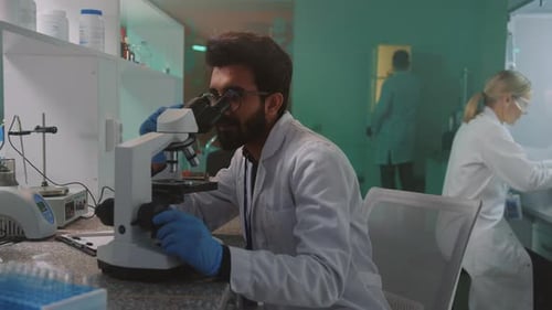 Focused Scientist Using Microscope in Modern Laboratory