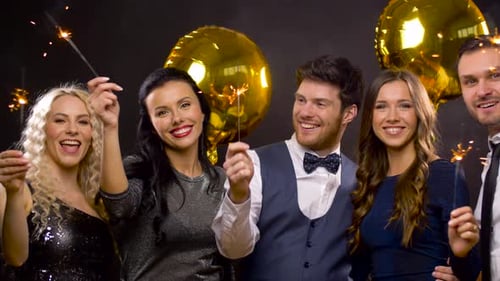 Friends smiling with sparklers and balloons at party