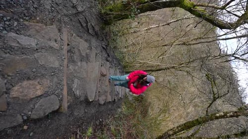 Woman climbing stone stairs during hike on Four Falls Trail, Wales. Vertical