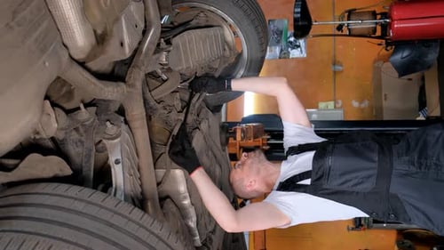 Auto Mechanic Working Underneath Car in Repair Shop