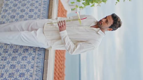 Young Man Holding Flower on Balcony