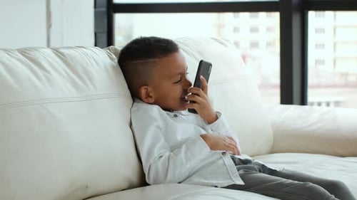 Happy Boy Chatting on Mobile Phone on Couch