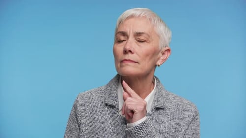 Contemplating Mature Woman on Plain Blue Background