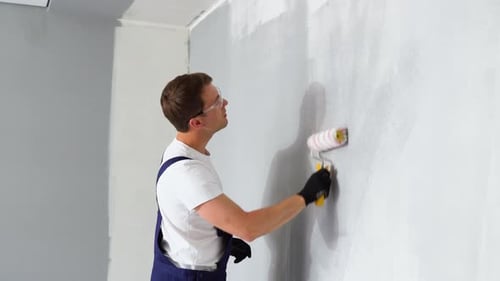 Young Adult Painting Wall Gray with Paint Roller