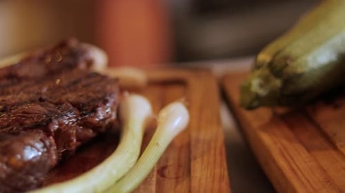 Grilled Steak with Spring Onion Garnish Served on a Wooden Cutting Board