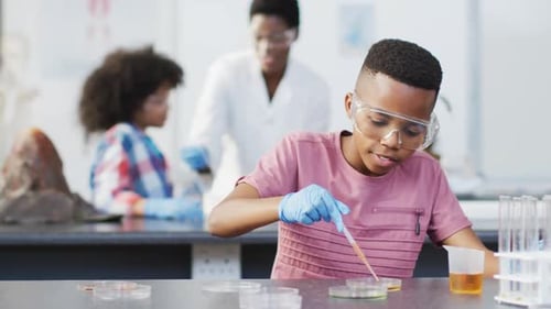 Diverse female teacher and happy schoolchildren having science class in school lab