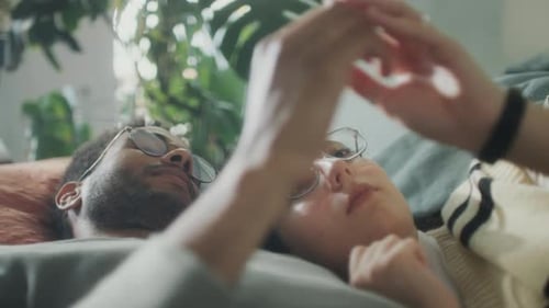 Loving Young Couple Holding Hands Lying Indoors