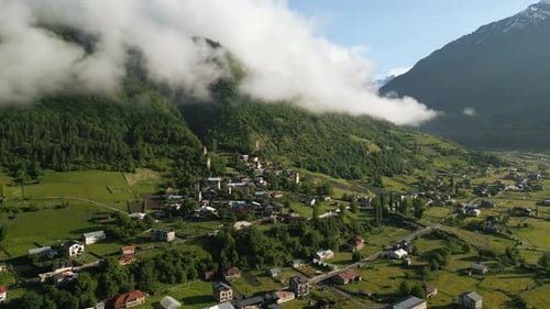Aerial View of Svan Towers in Mountain Valley at Sunrise Green Hills Low Clouds Historic Stone